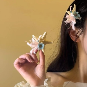 Detail of starfish hair claw clip with pink tassels and blue flowers on model