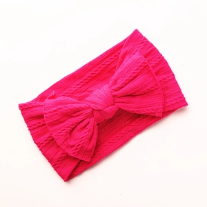 Detail of rose red nylon baby headband featuring a large jacquard bow and ribbed texture