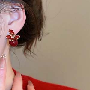 Detail of elegant red floral pearl stud earrings with sparkling crystals on female model