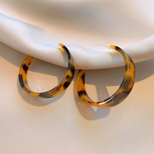 Close-up of leopard print resin hoop earrings on beige silk fabric background