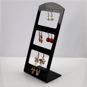 L-shaped black acrylic earring stand displaying pearl and crystal drop earrings