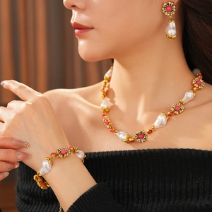 Close-up of vintage gold necklace set with baroque pearls and red gemstones on a model