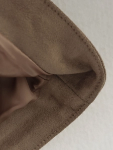 Detailed close-up of dark brown faux suede fabric with precise double stitching on edges