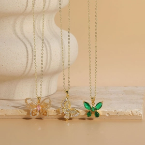 Close-up of golden butterfly pendant necklaces with pink, clear, and green zircon stones