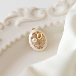 Close-up of golden tulip pendant with enamel frame and pearl detail on vintage tray