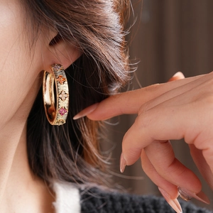 Gros plan de créoles plaquées or 18 carats avec accents floraux trèfle en zircon coloré