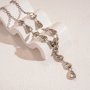 Minimalist silver metallic necklace with irregular water drop beads on an art stand