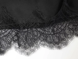 Macro shot of intricate black lace trim and smooth satin fabric detail on casual top