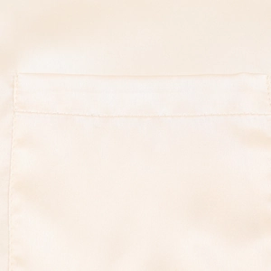 Nahaufnahme der beigen Satinbluse mit einer ordentlich vernähten Brusttasche