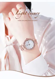 Close-up of rose gold watch with rhinestone bezel and white dial on a woman's wrist
