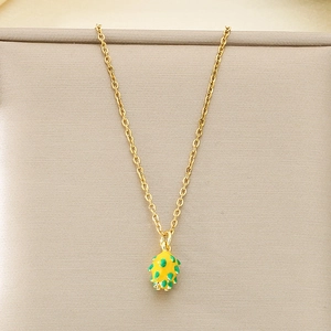 Detail of yellow dragon fruit pendant with green accents on a golden stainless steel chain