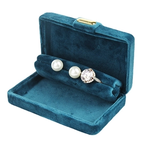 Teal velvet jewelry box with gold clasp and pearl earrings, tilted 45-degree angle view