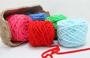 Dettaglio di gomitoli di lana spessa nei colori rosa blu rosso verde in scatola di legno