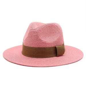 Detail of pink straw Panama hat featuring finely woven texture and a brown ribbon band