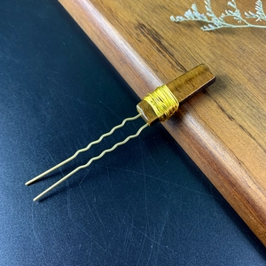 Close-up of handmade U-shaped wooden hair pin with gold wire wrap and crystal element