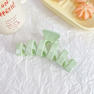 Detail of mint green matte hair claw clip with geometric hollow design on white paper