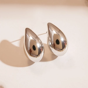 Macro shot of silver drop earrings with a high-polish mirror finish and minimalist design
