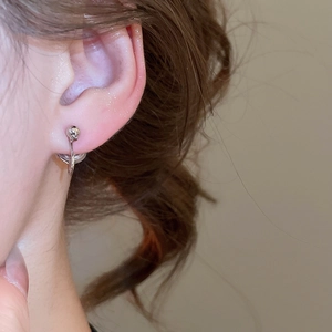 Close-up of minimalist silver geometric round earring worn on ear with soft lighting