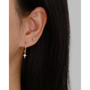 Close-up of minimalist s925 sterling silver four-pointed star earrings worn by a model