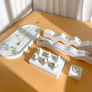 Golden jewelry set with heart necklace and rings on geometric plaster display stands