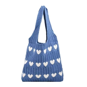 Knitted denim blue tote bag featuring white heart patterns and a thick cable stitch design