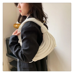 Detailed side view of white woven knot shoulder bag with a unique sculptural half-moon shape