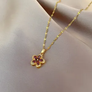 Close-up of golden necklace with red zircon flower pendant on champagne silk fabric