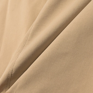 Detailed close-up of khaki trench coat fabric featuring twill texture and parallel stitching