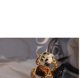 Close-up of vintage gold twisted rings featuring square black spotted and brown stones