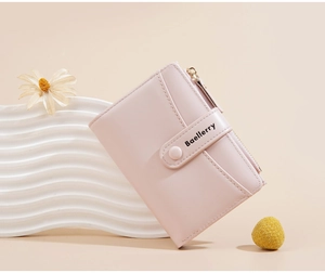 Close-up of pale pink leather compact wallet with snap button and smooth metal zipper