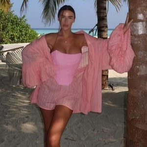 Texture détaillée de l'ensemble d'été rose avec haut tube et chemise sur plage tropicale