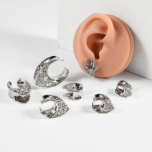 Macro detail of silver U-shaped ear tunnel featuring blue opal stone and hollow patterns