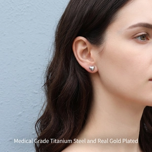 Polished silver heart stud earrings in titanium steel worn by model on ear