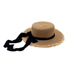 Detail of straw boater hat with frayed edges and long black ribbon for sun protection