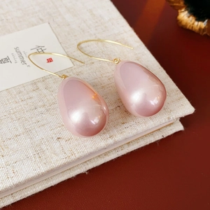 Vista macro di orecchini vintage con perle a goccia rosa e ganci dorati eleganti
