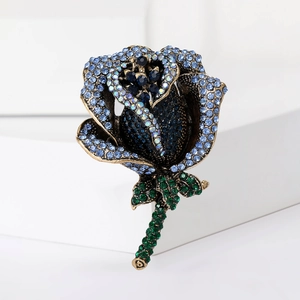Elegant rose brooch with blue and green crystals on a bronze metal base for suits