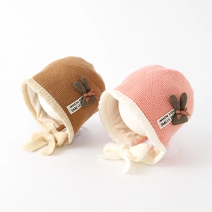 Knit baby winter hat with rabbit ears and tie straps in brown and pink colors