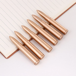 Penne a sfera creative a forma di proiettile in bronzo su un taccuino a righe
