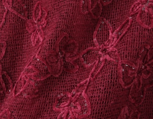 Detailed macro view of burgundy mesh fabric with floral flocking and sparkling sequins