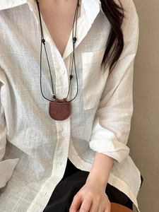 Close-up of brown faux leather magnetic glasses holder pendant on a black cord necklace