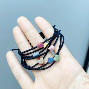 Handheld view of multi-color matte heart charms on high-elasticity black hair ties