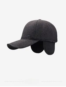 Detailed close-up of dark grey wool baseball cap with ear flaps and metal logo