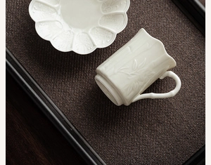 Top view of ceramic teacup with bamboo relief detail on dark woven tray