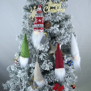 Five assorted Christmas gnome plush ornaments hanging on a flocked holiday tree