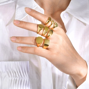 Polished gold geometric signet rings worn in a minimalist fashion on fingers