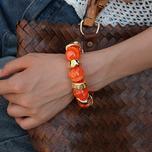 Detailed view of orange acrylic marble beads and chunky gold metal spacers on the bracelet