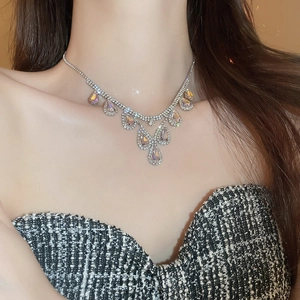 Close-up of model wearing silver rhinestone necklace with teardrop pendant charm