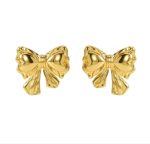 Detailed close-up of golden bow-shaped stud earrings with polished metallic texture