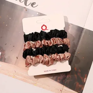 Detail of 4-pack satin scrunchies in black and champagne on a display card