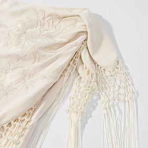 Détail de broderie florale et de glands tissés sur le tissu de jupe courte beige